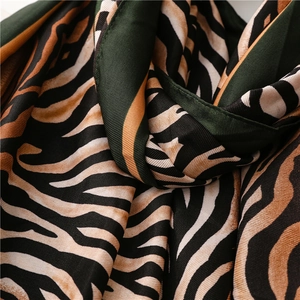 Detailed close-up of dark green zebra print silk scarf showing smooth fabric texture