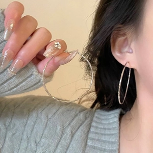 Silver geometric hoop earrings with sparkling rhinestones worn by a fashion model