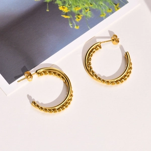 Close-up of golden C-shaped hoop earrings featuring a stylish twisted rope texture design