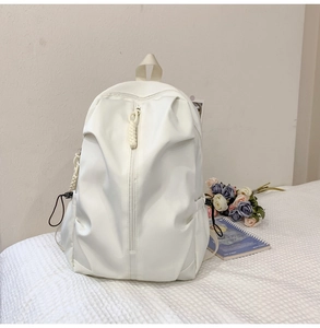 Flat lay of minimalist cream-white large-capacity backpack with notebook and dried flowers