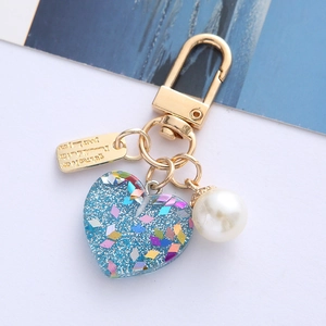 Detail of blue glitter heart pendant with white pearl and gold clasp keychain