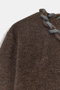Détail de la maille marron et de la bordure en corde tressée grise à l'encolure