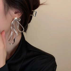 Détails de boucles d'oreilles nœud argenté avec strass brillants sur l'oreille