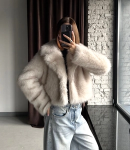 Detailed close-up of cream faux fox fur texture on a short loose-fit winter jacket