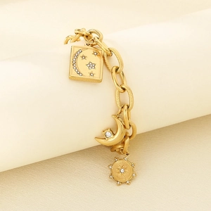 Detailed close-up of 18K gold star and moon charms on a thick link chain bracelet