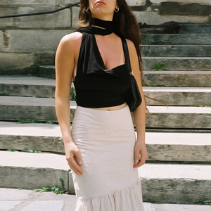 Detail of a black halter tie-up crop top paired with a cream ruffle mermaid skirt