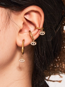 Macro view of gold-plated evil eye earrings and ear cuffs set with sparkling zircons