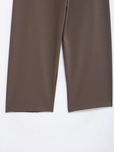 Detailed view of brown suit trousers hem showing smooth drape and fabric texture