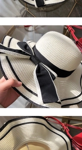 Detail of a beige straw sun hat featuring a wide brim and elegant black ribbon bow