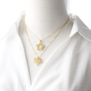 Elegant gold plated star and maple leaf pendant necklace with crystals on white shirt
