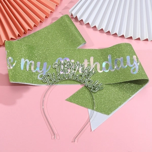 Close-up of green glitter sash and rhinestone tiara set on pink party background