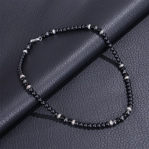 Detail of matte black stone beads with textured metal spacers and a secure lobster clasp