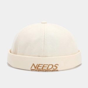 Close-up of beige docker hat with brown NEEDS embroidery on durable cotton twill fabric