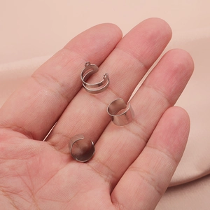Three creative silver stainless steel cuff earring accessories held on a soft background