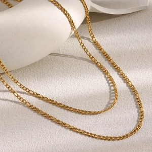 Close-up of elegant 18K gold plated double-layer Figaro chain necklace on a white vase