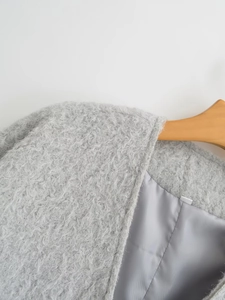 Detailopname van lichtgrijze pluche textuur en kraag op een houten kleerhanger
