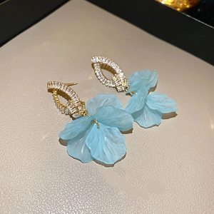 Détail de boucles d'oreilles fleur bleue avec cadre doré et zircon cubique marquise