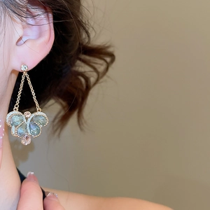 Detail shot of vintage crystal butterfly drop earring worn on model for fashion look