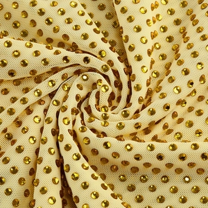 Détail macro du tissu en maille jaune avec strass ambrés et motif en spirale élégant