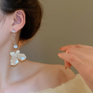 Détail de boucles d'oreilles fleur à pampilles avec pétales blancs et cristaux