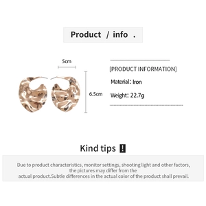 Détail de boucles d'oreilles en métal martelé irrégulier mesurant 5 cm par 6,5 cm