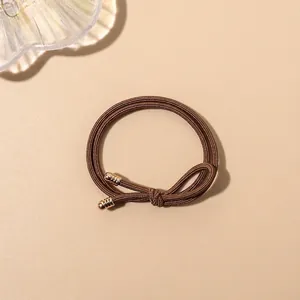 Close-up of brown high-elasticity braided hair tie with elegant gold spiral metal accents