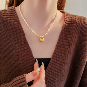 Detail of vintage Chinese style pearl necklace with golden longevity lock pendant