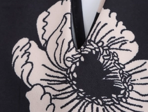 Detailed macro view of V-neckline and monochrome floral texture on woven fabric shirt