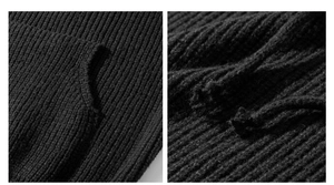 Close-up of black cable knit texture showing ribbed cuffs and woven drawstring details