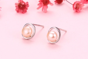 Macro shot of pink gold freshwater pearl earrings with silver circular metal detail