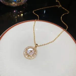 Détail macro du pendentif croix plaqué or 18K avec nacre et zircons étincelants