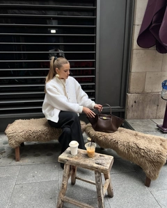 Chic styling of a white sherpa bomber jacket with black wide-leg trousers and gold earrings