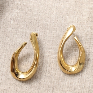 Close-up of golden twisted hoop earrings on a textured beige linen fabric background
