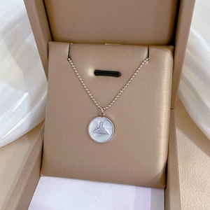 Detail of silver T-shaped pendant with white shell inlay in a beige gift box