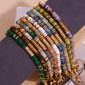 Detail von bunten Steinperlen und goldenen Distanzstücken an mehrlagigen Armbändern