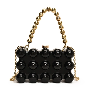 Detail of black acrylic clutch with 3D bubble texture, gold beaded handle and chain
