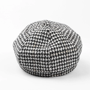 Macro view of black and white houndstooth pattern fabric with a top button on a beret hat
