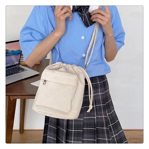 Chic beige nylon drawstring crossbody bag shown on model in a cozy study setting