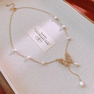 Macro shot of gold-plated butterfly necklace with freshwater pearls and zircon accents