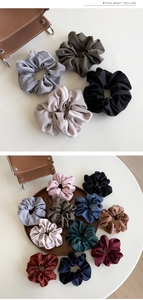 Detailed view of assorted satin scrunchies in vintage colors on a wooden tray