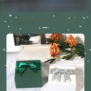 Close-up of square jewelry gift boxes in dark green and white with satin ribbon bows