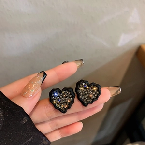 Détail d'une boucle d'oreille cœur noir avec strass scintillants et placage en or