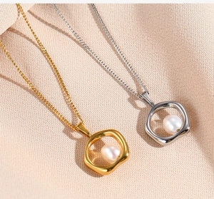 Detail of gold and silver irregular ring pendants with pearls on beige fabric background