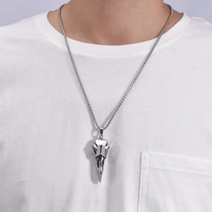 Close-up of a silver stainless steel crow skull pendant on a long box chain for men