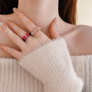 Close-up of elegant beaded bow ring with crystals worn on finger in a cozy soft setting