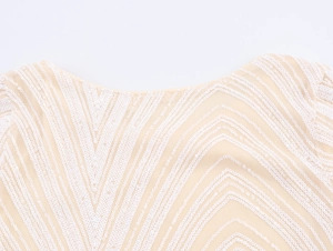 Detail of V-neckline with white sequins and nude mesh in a geometric wavy pattern