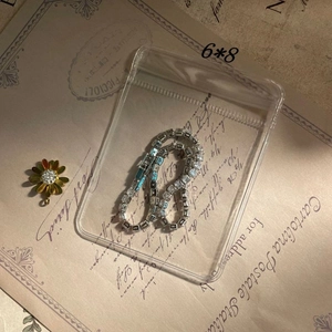 Detailed view of jewelry in a 6x8cm clear zip bag on a vintage Italian postcard
