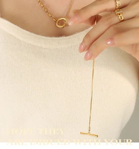 Detail of 18k gold plated OT buckle necklace and square zircon ring on knitwear