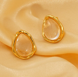 Detailed view of teardrop titanium earrings with gold frame and clear resin stone inlay