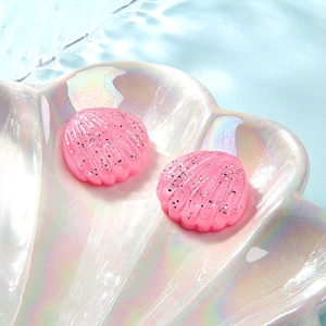 Macro shot of pink glitter resin shells in an iridescent shell plate over water